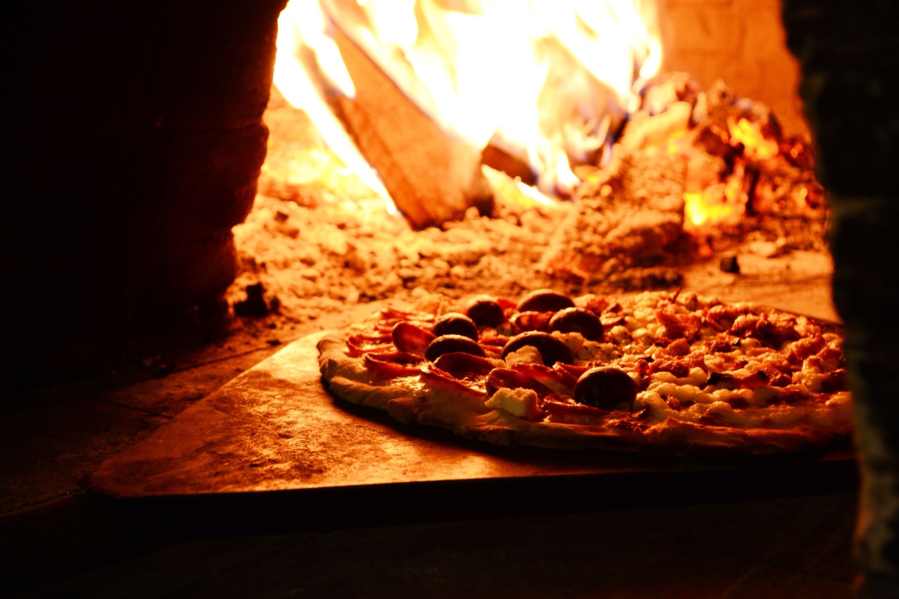 Pizza cooking in the flames of a wood-fired oven