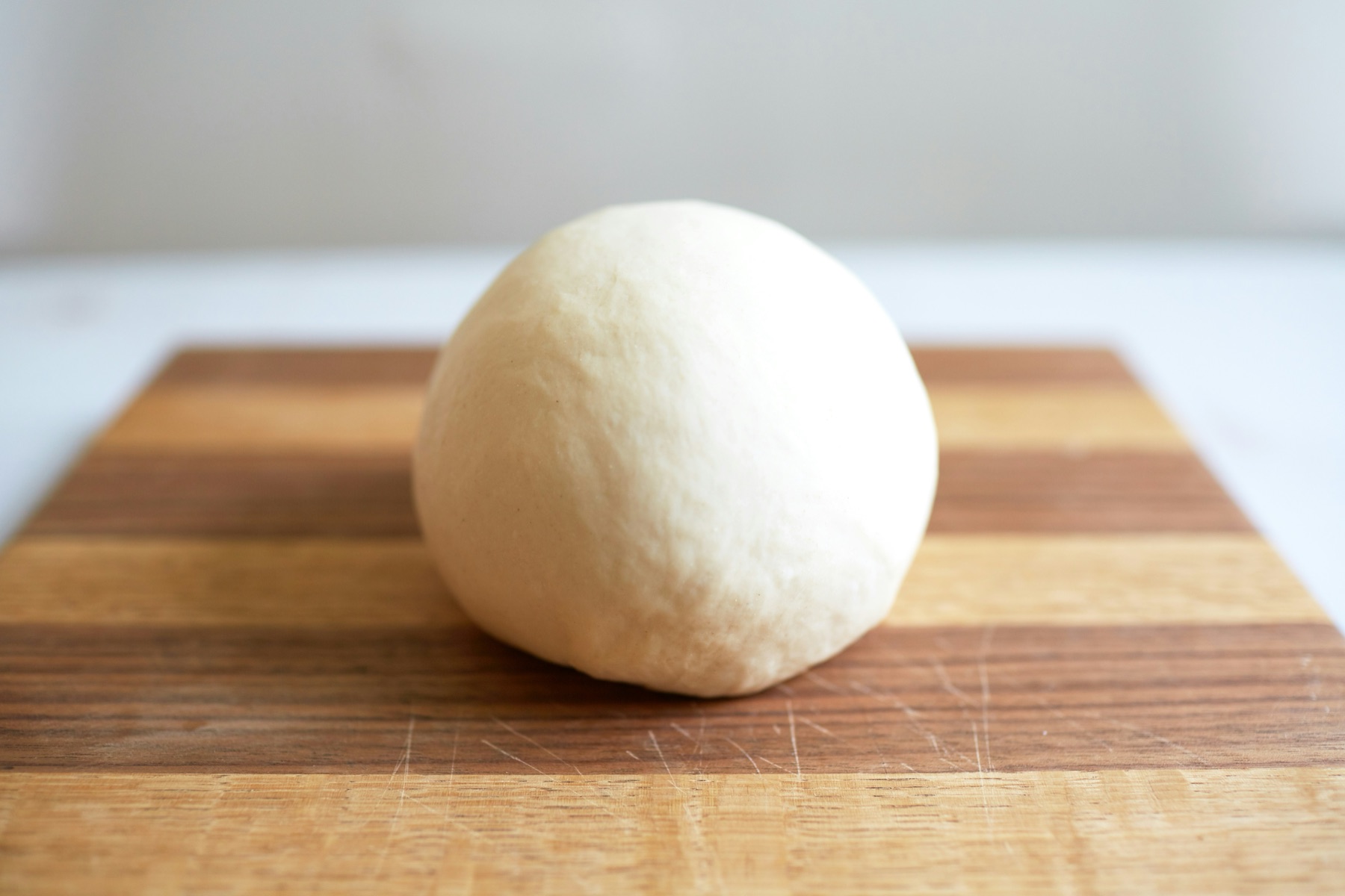 A single prepared pizza dough ball on a wooden board