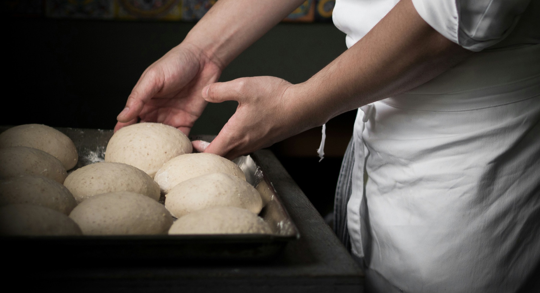Chef preparing a tray of pizza dough balls