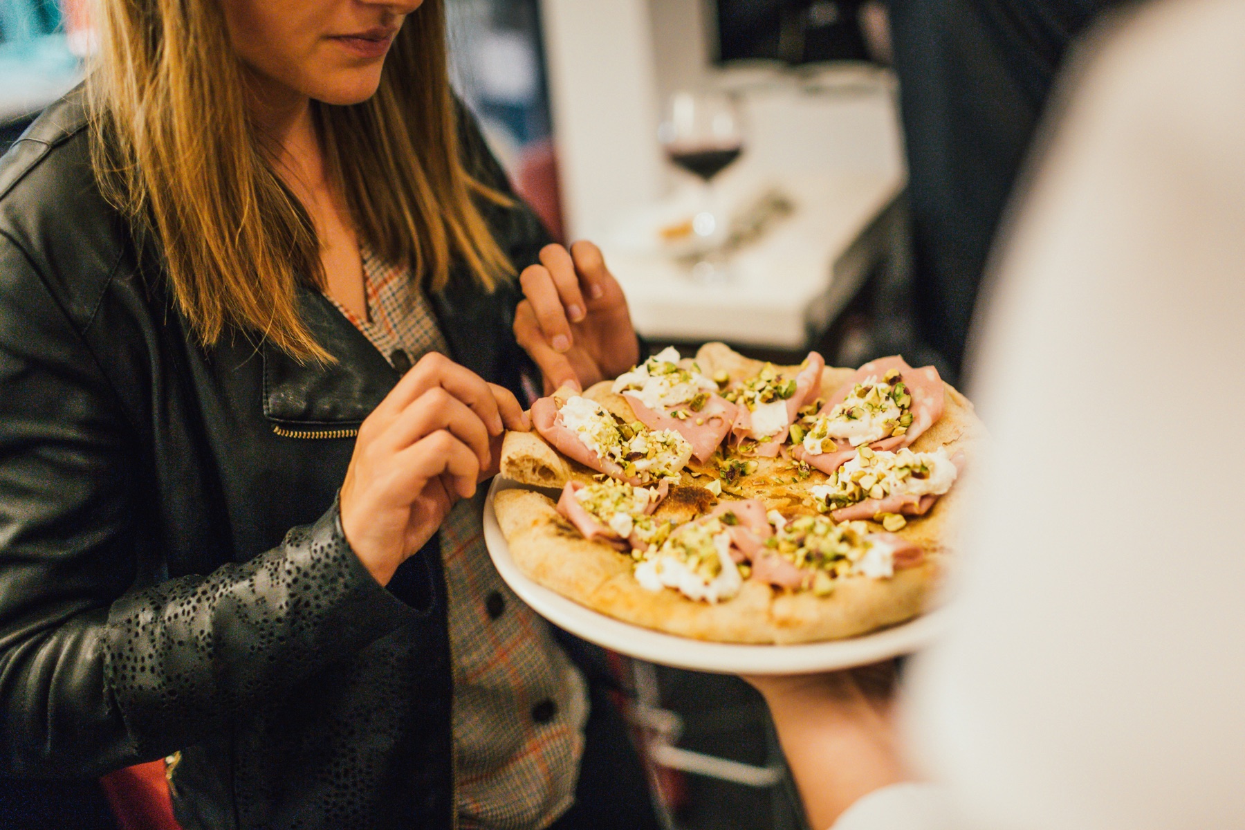 A guest being served a freshly cooked pizza