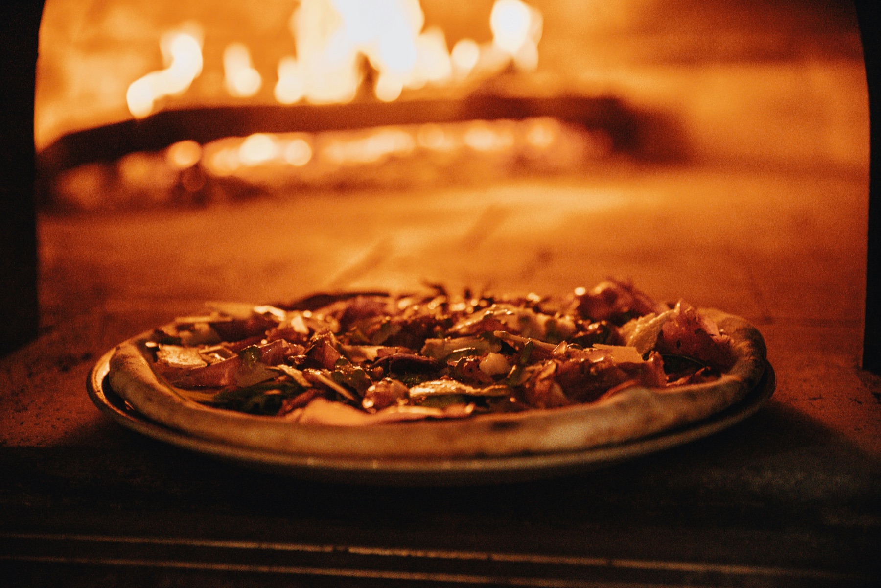 Pizza cooking in the warm glow of a wood-fired oven