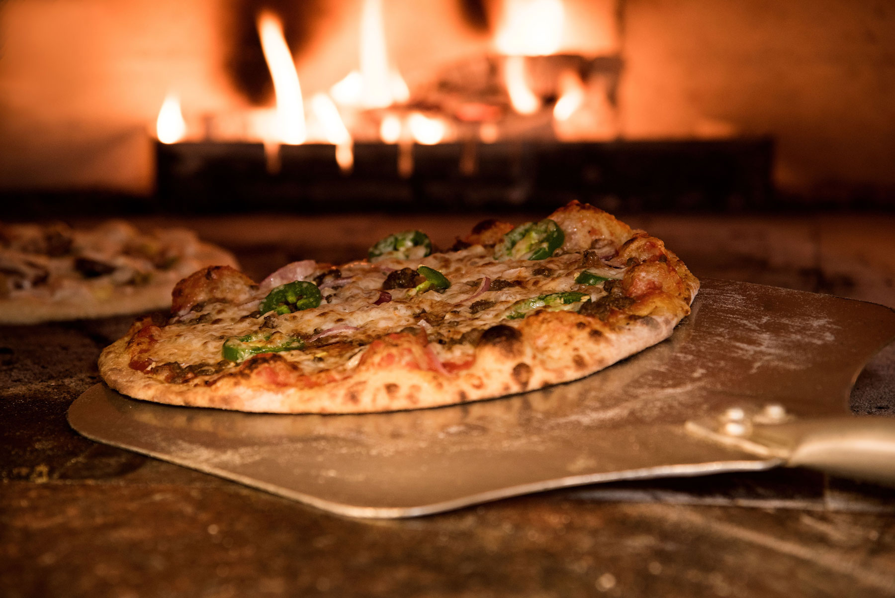 Wedding guests gathering around outdoor wood-fired pizza catering