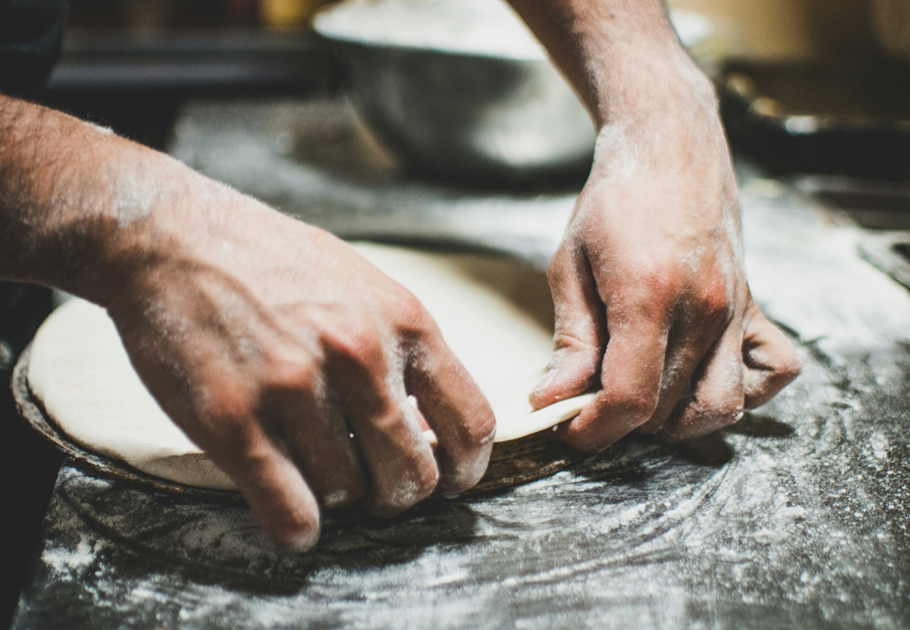 Pizza chef shaping dough on a floured work surface